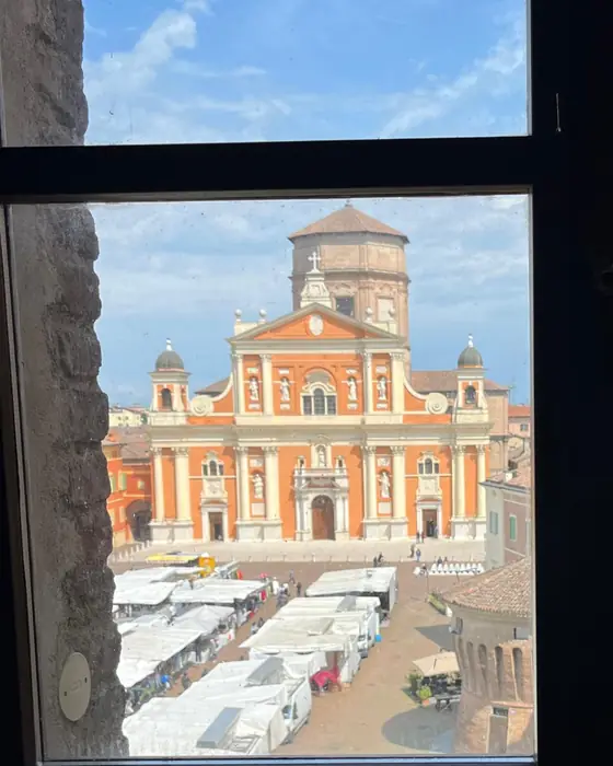 The cathedral of Carpi and its market square, seen through a castle window near Modena